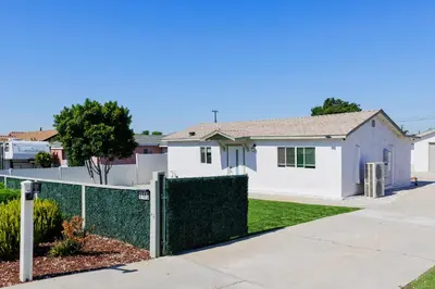 a fence in front of a white house at Cozy and Quiet Front House in Fontana