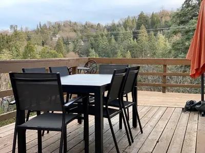 a black table and chairs on a wooden deck at Beautiful Lake View House for rent! in Lake Arrowhead