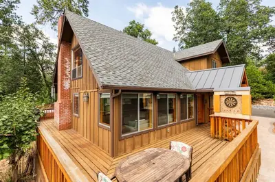 a house with a wooden deck with a table and chairs at Sequoia Retreat- Spacious Cabin, Hot tub, & Sundeck in Ponderosa