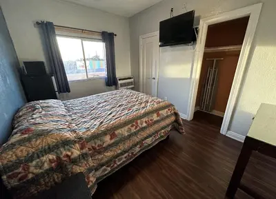 a bedroom with a bed and a flat screen tv at Unity Hotel - No Parking & Rooms Are Upstairs in Long Beach