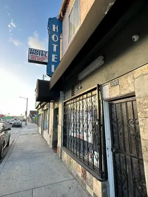 a building on a street with a gate and a sign at Unity Hotel - No Parking & Rooms Are Upstairs in Long Beach