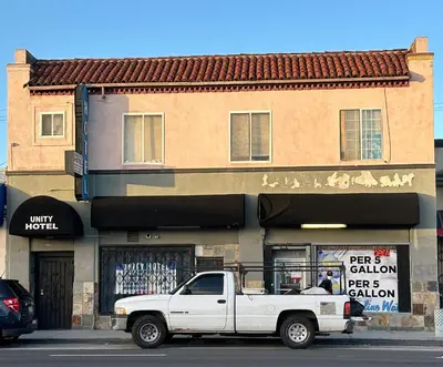 a white truck parked in front of a building at Unity Hotel - No Parking & Rooms Are Upstairs in Long Beach