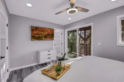 a white bedroom with a bed and a ceiling fan at Tree-Lined Lake Arrowhead Cabin about 1 Mi to Village! in Lake Arrowhead