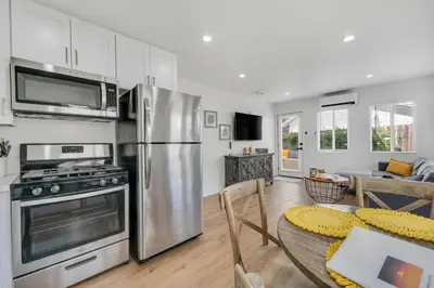 a kitchen with a stainless steel refrigerator and a table at Modern Cottage, Hot Tub, Bistro Patio, Putting Green, Walk to All! in Thousand Oaks