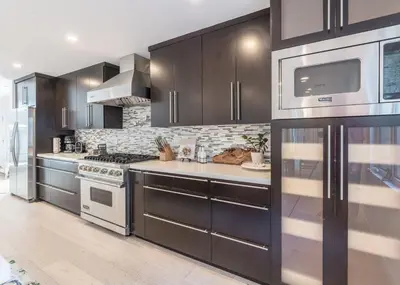 a kitchen with stainless steel appliances and black cabinets at Cali Luxury Dream Hideaway in Woodland Hills