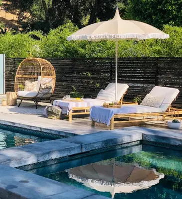 a patio with an umbrella and chairs and a pool at Cali Luxury Dream Hideaway in Woodland Hills