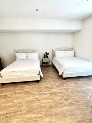 two beds in a white room with wooden floors at Studios Universal 10 min drive FREE parking and WIFI in Los Angeles