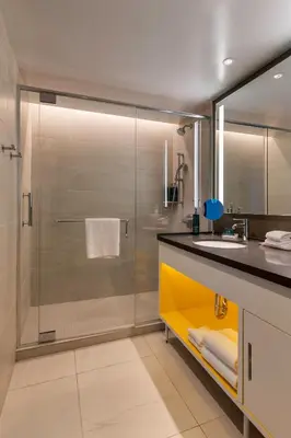 a bathroom with a glass shower and a sink at Hilton Buena Park Anaheim in Buena Park