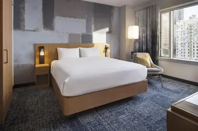 a bedroom with a large white bed and a chair at Courtyard by Marriott Los Angeles L.A. LIVE in Los Angeles