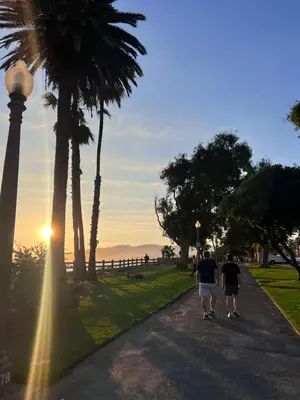 two people walking down a road with palm trees at Arion- Cozy Santa Monica getaway steps to the beach Free Parking in Los Angeles