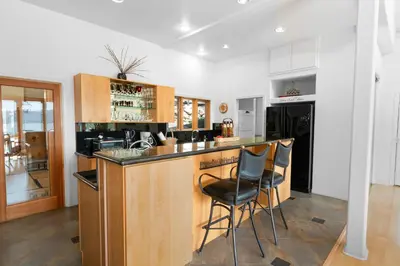 a kitchen with a bar with two chairs at it at Amazing Grace - Zen mountain retreat with lake views in Fawnskin