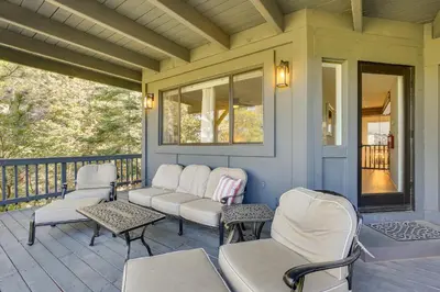 a porch with chairs and tables on a house at 3 Decks, Game Room and Views Lake Arrowhead Home! in Lake Arrowhead