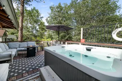 a hot tub on a patio with an umbrella at Clerestory Cottage - The perfect cozy getaway with a hot tub in Big Bear Lake