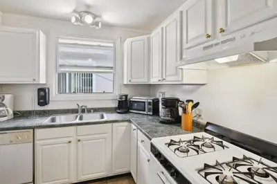 a kitchen with white cabinets and a stove top oven at Walk to Retro Row Long Beach Condo in Long Beach