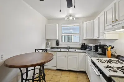 a kitchen with white cabinets and a wooden table at Walk to Retro Row Long Beach Condo in Long Beach