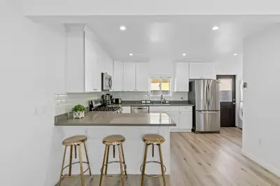 a kitchen with white cabinets and bar stools at Muirfield Chic City Bungalow with Parking 1,2,3 in Los Angeles