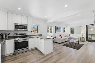 a kitchen and living room with white cabinets at Muirfield Chic City Bungalow with Parking 1,2,3 in Los Angeles