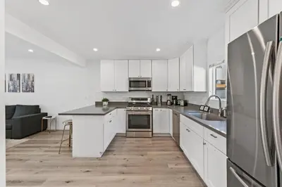 a kitchen with white cabinets and a stainless steel refrigerator at Muirfield Chic City Bungalow with Parking 1,2,3 in Los Angeles