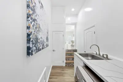 a white kitchen with a sink and a painting on the wall at Universal Studios Villa with Pool & Guesthouse in Los Angeles