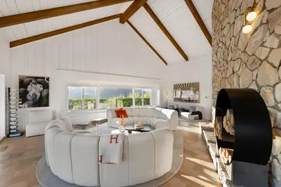 a living room with white furniture and a stone fireplace at Beverly Tree House in Los Angeles