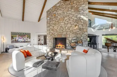 a living room with white furniture and a stone fireplace at Beverly Tree House in Los Angeles