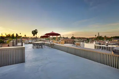 a rooftop deck with tables and an umbrella at NEW Luxury Concrete Home Just Minutes from the Beach in Long Beach