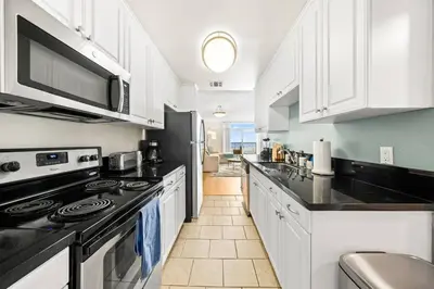 a kitchen with white cabinets and black appliances at Smoky Quartz -Marina View Spacious 3BR near Yacht Club in Los Angeles