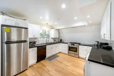 a kitchen with white cabinets and a stainless steel refrigerator at Modern Pine Mountain Club Cabin with Community Pool! in Pine Mountain Club