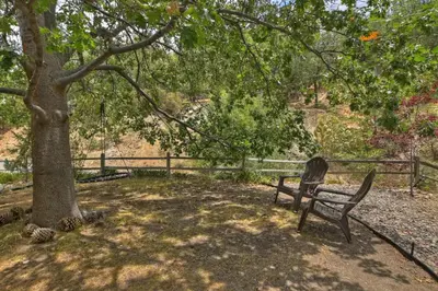 a park bench under a tree next to a fence at Jackalope Lodge in Lake Arrowhead