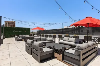a patio with couches and tables and an umbrella at Hotel Mai Downtown Long Beach in Long Beach