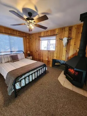 a bedroom with a bed with a fireplace and a ceiling fan at The Ponderosa in Running Springs