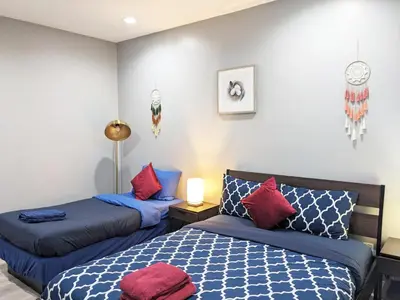 two beds in a room with blue and red pillows at Lucky Charm 4 Bedroom Mid-City Apartment in Los Angeles