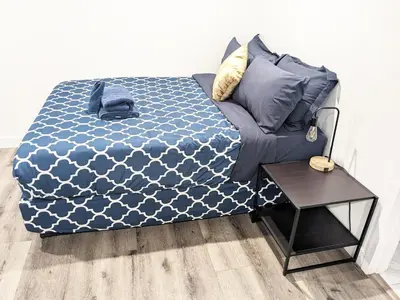 a bed with a blue comforter and a side table at Wonderful 3 Bedroom Home Perfect for Getaway in Los Angeles