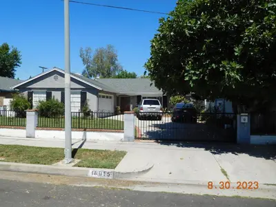 a house with a fence and a car parked in a driveway at Nice Northridge 4-2-2 home near CSUN and Pierce College in Northridge
