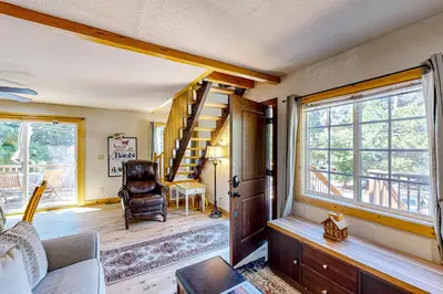 a living room with a staircase and a chair at Heliotrope Hideaway in Lake Arrowhead