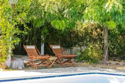 two wooden chairs sitting next to a swimming pool at Newly Furnished Pool House in Los Angeles