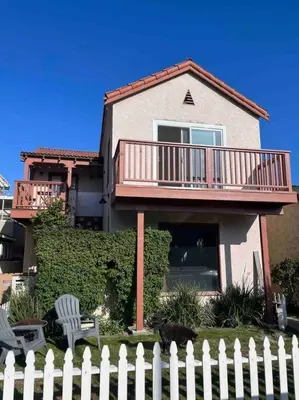 a white fence in front of a house with a deck at Huge Updated Spanish Apt - Steps to Beach & Bay! in Long Beach
