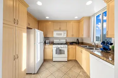 a kitchen with wooden cabinets and a white refrigerator at Beverly Hills Penthouse 2 BR Apt with Parking 407 in Los Angeles