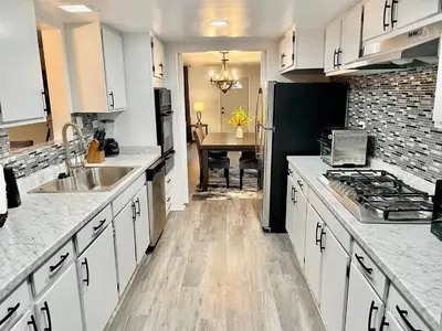 a kitchen with white cabinets and a black refrigerator at Glendora Pool Home Retreat in Glendora