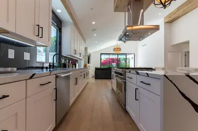 a large kitchen with white cabinets and a long hallway at Universal Studio Stellar Home with pool and jacuzzi in Los Angeles