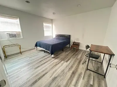 a bedroom with a bed and a desk and a chair at Little Bettys Cottage in Torrance