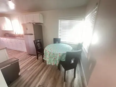 a kitchen with a table and chairs and a refrigerator at Little Bettys Cottage in Torrance