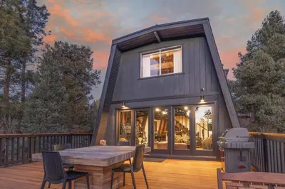 a small black house with a table on a deck at Stunning Cabin with Private Deck in Big Bear City