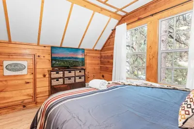 a bedroom with a bed and a tv andwindows at Mountain Getaway in Big Bear Lake
