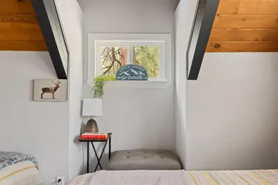 a bedroom with a window with a bed and a stool at Brunos Bungalow in Big Bear Lake