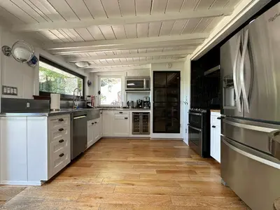 a large kitchen with white cabinets and a wooden floor at Malibou Lake Oasis in Agoura Hills