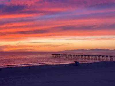 a sunset over a beach with a pier at The Vurpillat in Hermosa Beach