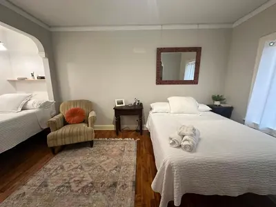 a bedroom with two beds and a chair and a mirror at The Vurpillat in Hermosa Beach