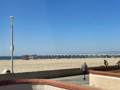 a person walking on a sidewalk near the beach at The Vurpillat in Hermosa Beach