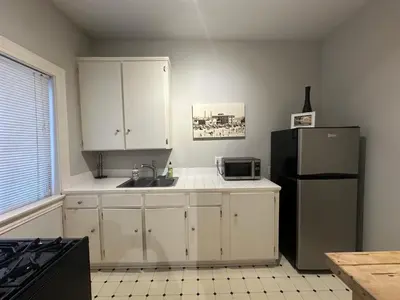 a kitchen with white cabinets and a black refrigerator at The Vurpillat in Hermosa Beach